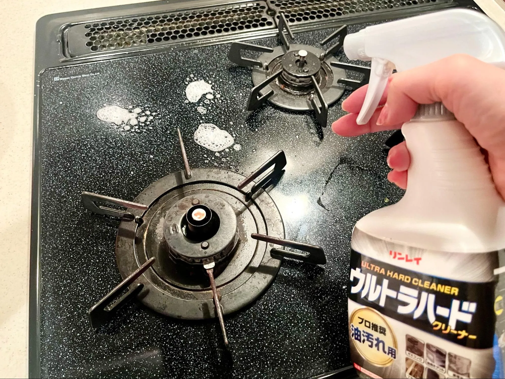 油汚れ専用の洗剤でコンロを掃除している様子