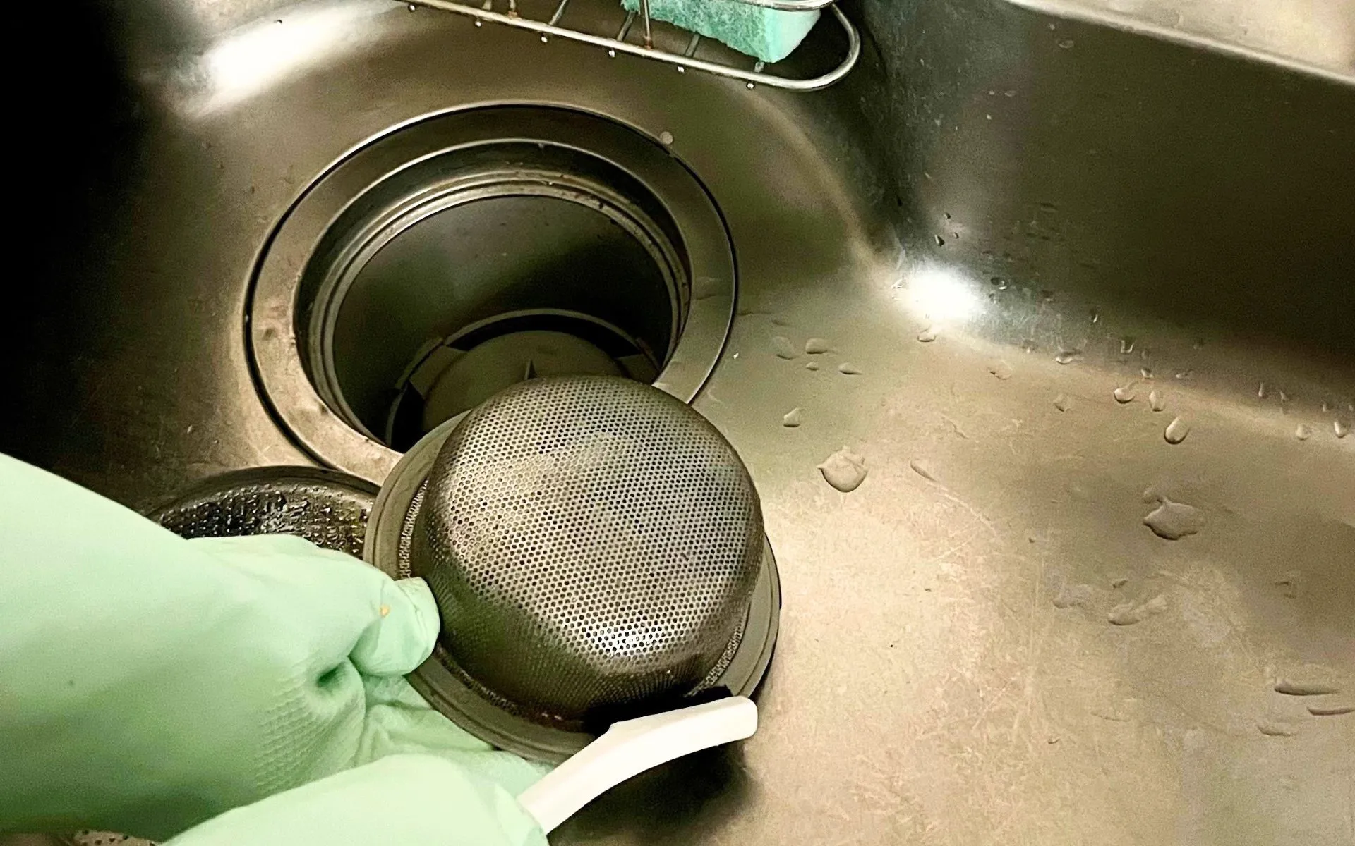 排水口のゴミ受けをブラシで掃除する様子